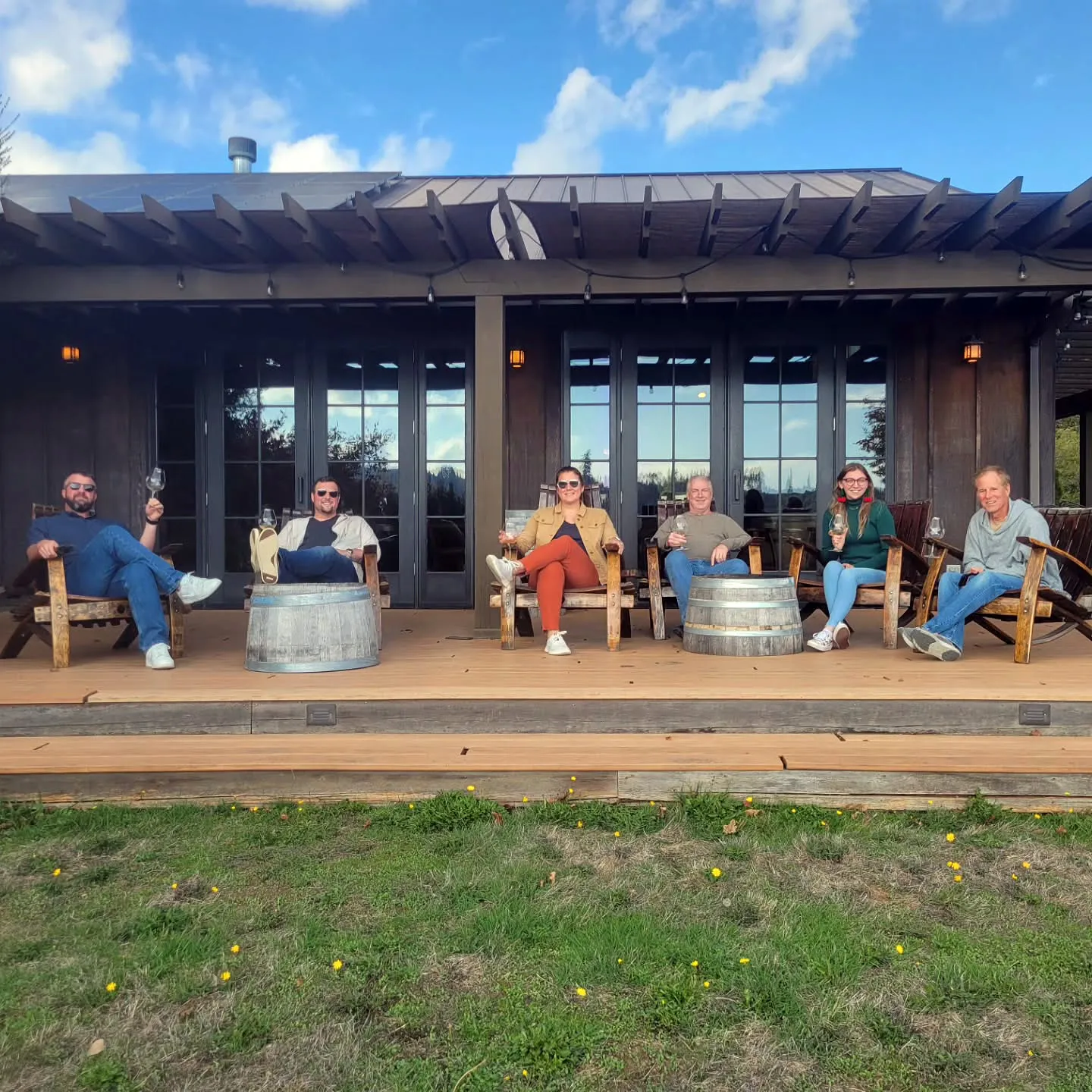 Small group relaxing with wine on a covered patio at a McMinnville winery in Oregon&rsquo;s Willamette Valley